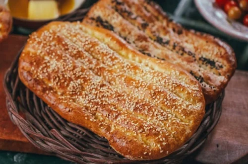 Kaksi leipää lepää puupöydällä, ja pitaleipä ohje on esillä maalaismaisessa ympäristössä.