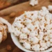 Kulhollinen popcorn-kaloritia sekoitettuna manteleihin ja valkosipuliin, joka esittelee suolaisen välipalasekoituksen.